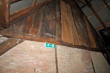 <p>Ter hoogte van gebint nummer 3 is op zolderniveau een scheidingswand aangebracht waarvan het bovenste deel met vertikaal eiken beschot is uitgevoerd. </p>
